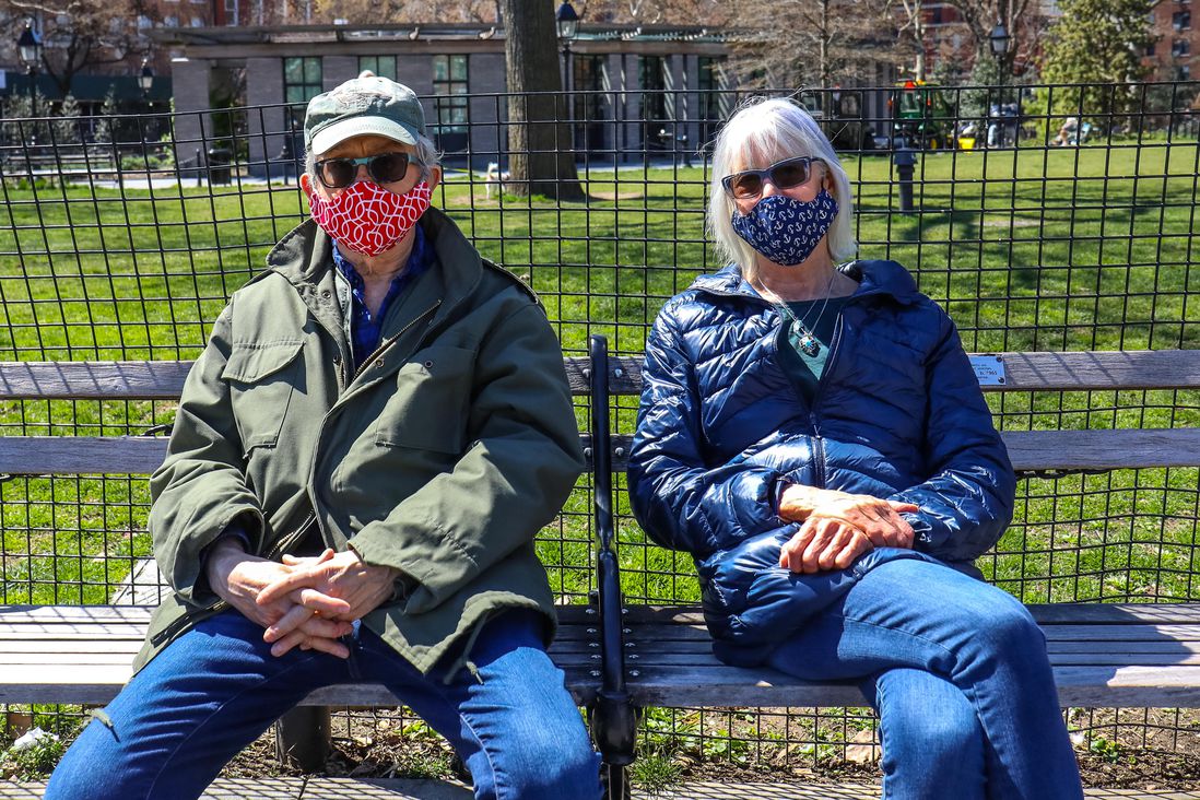 a man and woman on bench wearing masks